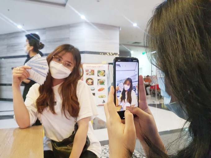2022년 4월 하노이의 한 영화관에서 20세 여성이 영화를 보며 티켓을 과시하기 위해 사진을 찍고 있다.
