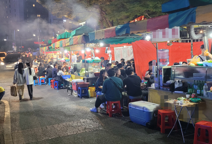 *포장마차 When you visit Korea for the first time, you will notice some tents arranged in rows. When you move closer, you will realize the tents have tables, chairs, food, and people. People get together under a tent to enjoy food and drinks as they enjoy the surrounding heaters to beat the cold. Such a place is known as pojangmacha