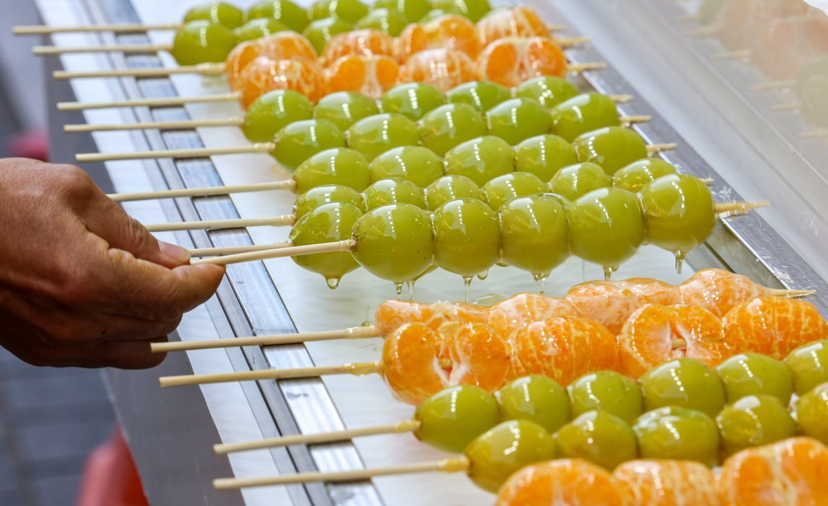 [출처: 동아일보] 길거리에서 샤인머스캣 탕후루와 귤 탕후루를 판매하고 있는 모습.