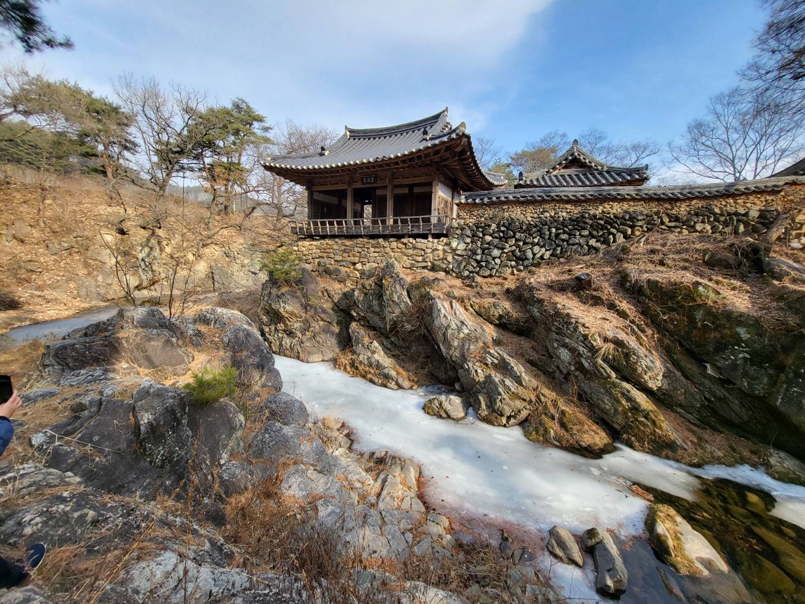 <초간정 남측 전경> 암반 위에 세워진 장수지소, 초간정은 금곡천 계류가 만든 거대한 충적암 암반 위에 축대를 쌓아 조성되었다. 사진은 남쪽 하류에서 북쪽을 향해 올려다본 시점으로, 초간정의 입지 특성을 극명하게 보여준다. 예천 초간정 남측에서 바라본 전경 (2023.02.06.)