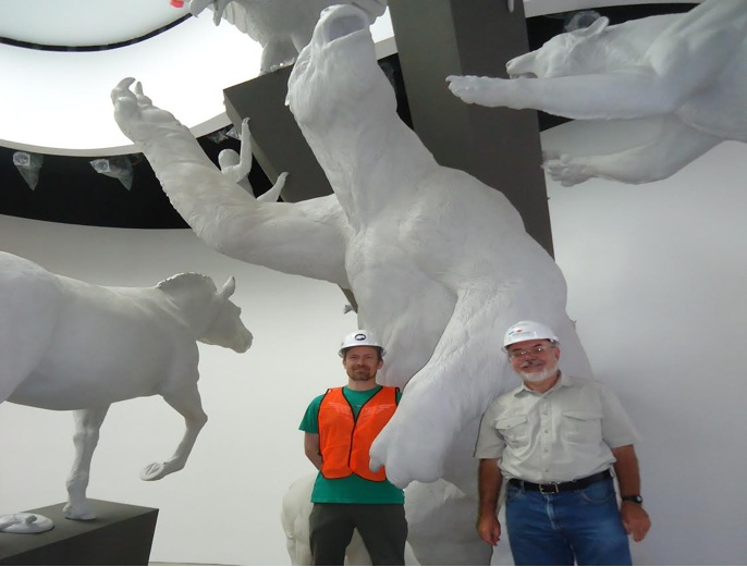 Photograph of George Angehr (right) and Jim Burt (left), lead sculptor of the animal figures, at the installation phase of the Worlds Collide Sculpture exhibit at Biomuseo. Credit: George Angehr.
