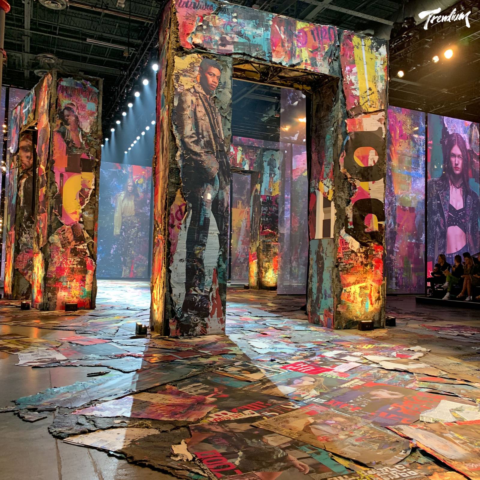 [prompt] fashion show runway stage, collage installation backdrop, oversized torn magazine fragments, bold typographic panels, layered translucent screens, high fashion editorial atmosphere