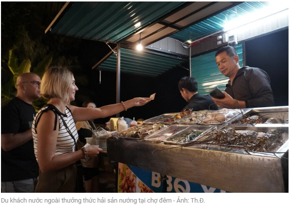 야시장에서 해산물 구이를 맛보는 외국인 관광객