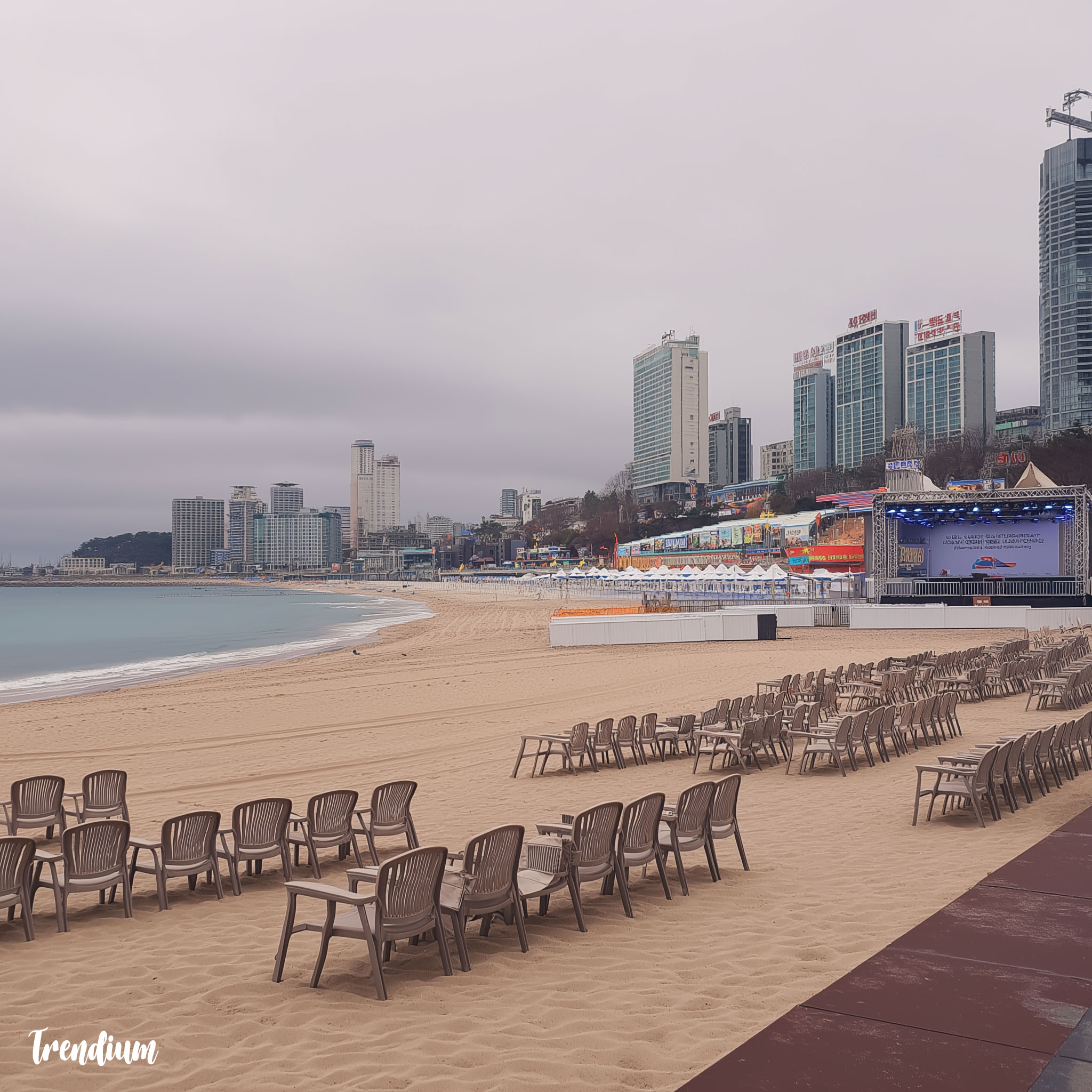 [prompt] Haeundae Beach on an off-season cloudy day, no tourists, empty beach chairs, overcast sky, gray sea, closed food stalls, surreal coastal stillness, liminal seaside space --v 7