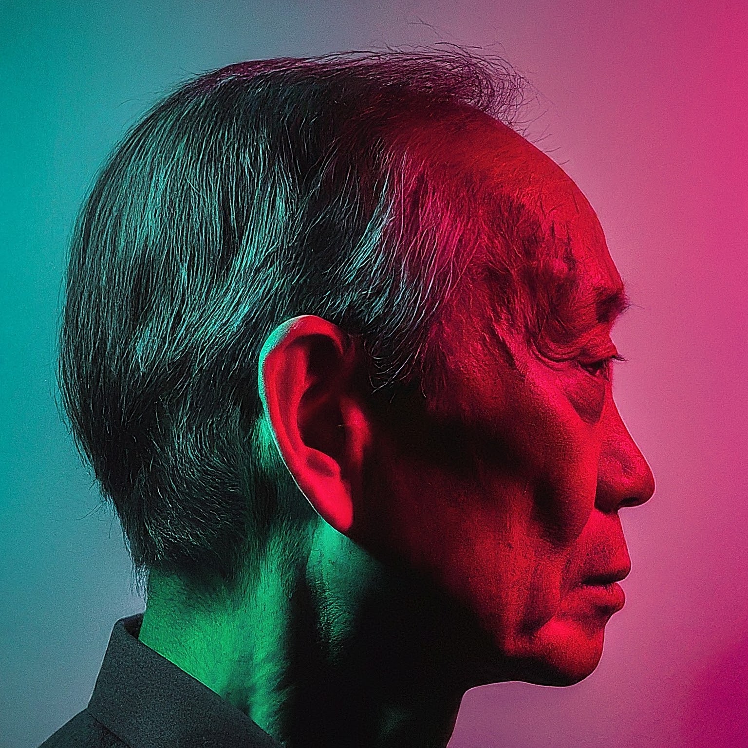 Side profile fashion headshot of an old adult Asian male model silhouette apart from a red rim light on the right and a teal rim light on the left